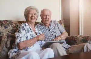 Happy elderly couple with digital tablet at home